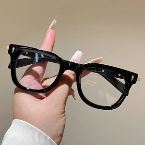 Detail view of black square frame glasses featuring gold metallic pointed accents on the sides