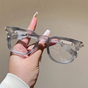 Close-up of matte grey cat-eye frames featuring golden diamond rivets and metal hinges