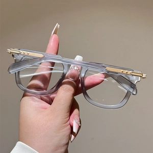 Detail of grey translucent cat-eye frame with striped gold metal hinge accents