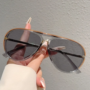 Detail of pilot sunglasses with grey frame, orange top bar, and gold metal accents