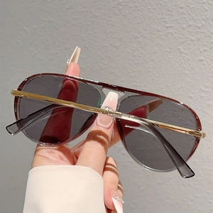 Detailed close-up of pilot sunglasses with grey translucent frame and gold metal bridge