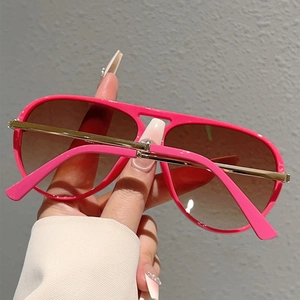 Close-up of pink pilot sunglasses with gold metal temples and gradient brown lenses