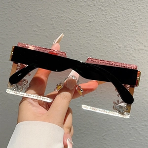 Detail of rimless square sunglasses with pink rhinestones and a spider chain charm