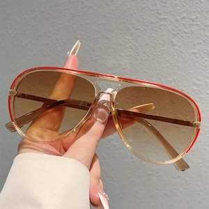 Detail of transparent tea-colored pilot sunglasses with a stylish red top bar accent