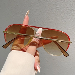 Close-up of red and gold aviator sunglasses with brown gradient lenses and metal temples