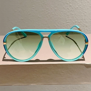 Detail of blue aviator sunglasses with gold double bridge and gradient lenses