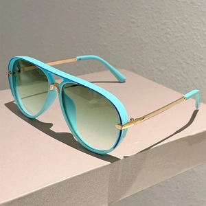 Detail of aviator sunglasses with cyan frame, gold metal temples and gradient green lenses