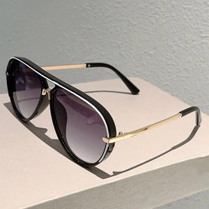 Detail of aviator sunglasses with gold metal temples and black frames with white trim