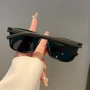 Close-up of black retro square sunglasses featuring textured diamond-pattern frames