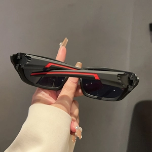 Detail of matte black sports sunglasses with vibrant red stripe accents on the temple