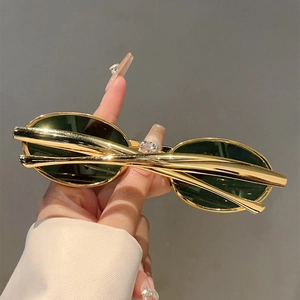 Détail de lunettes de soleil ovales vintage avec monture en métal doré pour femme