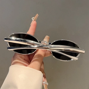 Détail des lunettes de soleil ovales à monture argentée et verres foncés style rétro