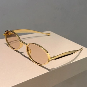 Détail de lunettes de soleil ovales vintage avec monture en métal doré et verres marron