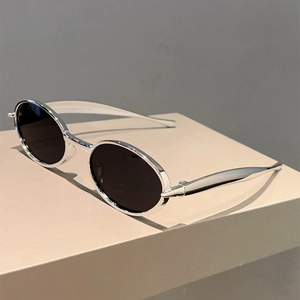 Détail de lunettes de soleil ovales avec monture argentée et verres noirs sur support