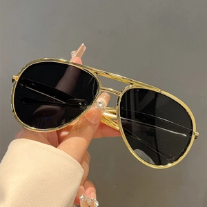 Close-up of classic pilot sunglasses featuring gold metal double bridge frames and dark lenses