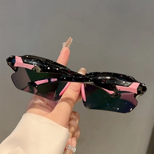 Close-up of black oversized sunglasses featuring pink accents and speckled pattern on arms