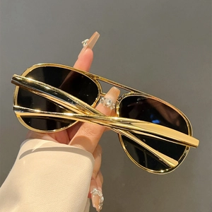 Detail of pilot sunglasses with gold metal double bridge frame and dark lenses