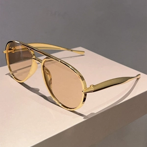 Detail of pilot sunglasses with gold metal frame and tan lenses on display stand