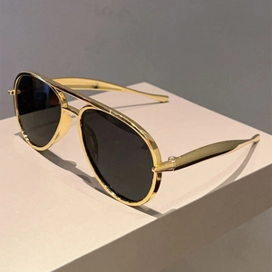Close-up of classic gold metal aviator sunglasses with black lenses and double bridge