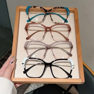 Close-up of stylish oversized cat-eye glasses frames in multiple colorways on a wooden tray