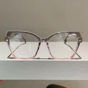 Detail of cat-eye glasses frame featuring a purple to pink gradient and gold accents