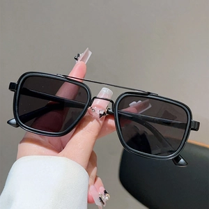 Détail de lunettes de soleil noires carrées avec double pont vintage tenues à la main