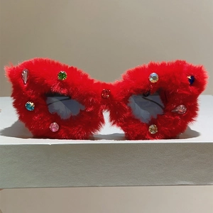 Détail de lunettes de soleil en peluche rouge avec strass colorés sur un présentoir