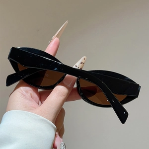Close-up of vintage cat-eye sunglasses with black frame and brown lenses held by hand