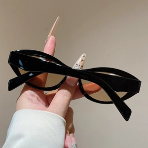 Detail view of retro cat-eye sunglasses with glossy black frames and amber lenses