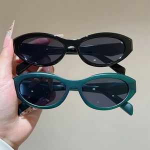 Detail view of retro oval cat-eye sunglasses in black and dark green glossy frames