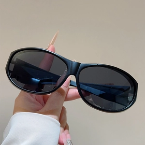 Détail des lunettes de soleil sport ovales noir mat avec verres gris polarisés en main