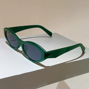Side view of deep green oval cat-eye sunglasses on a minimalist geometric block