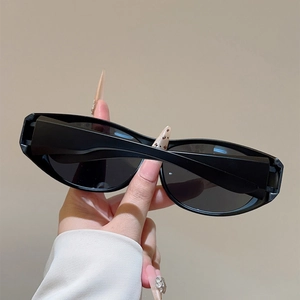 Gros plan de lunettes de soleil ovales noires tenues à la main montrant la monture lisse