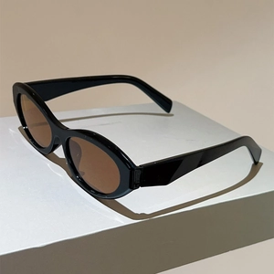 Detail view of stylish oval sunglasses featuring thick black frames and brown lenses