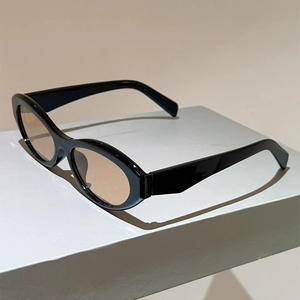 Retro cat-eye sunglasses with thick black frames and tinted lenses on a grey stand
