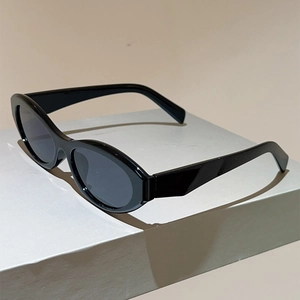 Detail view of premium black cat-eye sunglasses with thick frames on white geometric stand