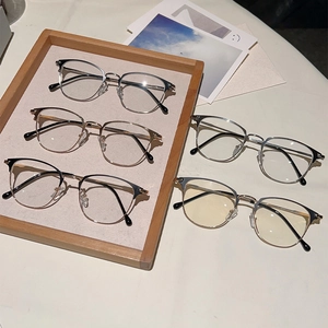 Retro semi-rimless metal glasses frames in multiple colors displayed on a wooden tray
