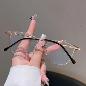Close-up of stylish gold metal eyeglass frames with black temples held in hand