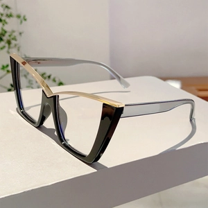 Detail view of modern cat-eye glasses with black and gold frames on a geometric stand
