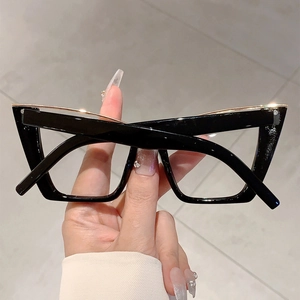 Detail of oversized cat-eye glasses with black frame and golden metal top bar detail
