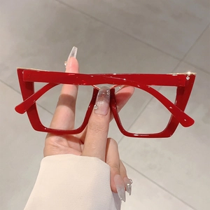 Detail of red oversized cat-eye glasses with gold metal trim and glossy thick frames