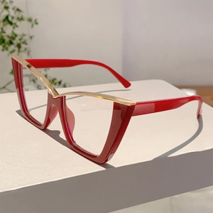 Detail of red cat-eye glasses with gold metal bridge on a neutral pedestal display