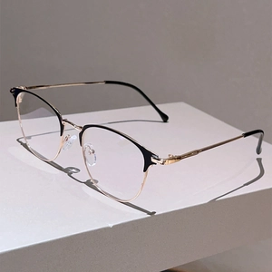 Detail of semi-rimless black and gold metal glasses frame on a minimalist pedestal