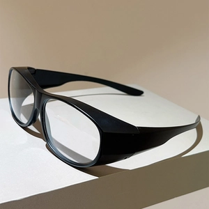 Détail des lunettes de cyclisme noires avec monture large sur un support blanc épuré