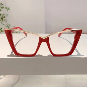 Detail of red cat-eye glasses with golden metal bridge on a white display stand