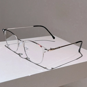 Detailed view of silver metal eyeglass frame with minimalist design on white pedestal