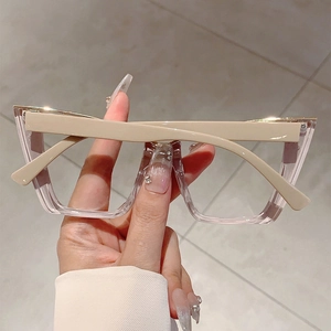 Detail of oversized cat-eye glasses with champagne frames and golden metal accents