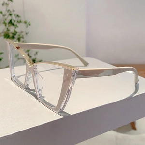 Detail of cream cat-eye glasses frame with sleek golden metal bridge on white steps