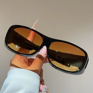 Detail view of large frame sunglasses with thick black frames and amber gradient lenses