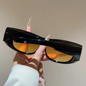 Detail of black sporty sunglasses with amber tinted lenses and rectangular frame